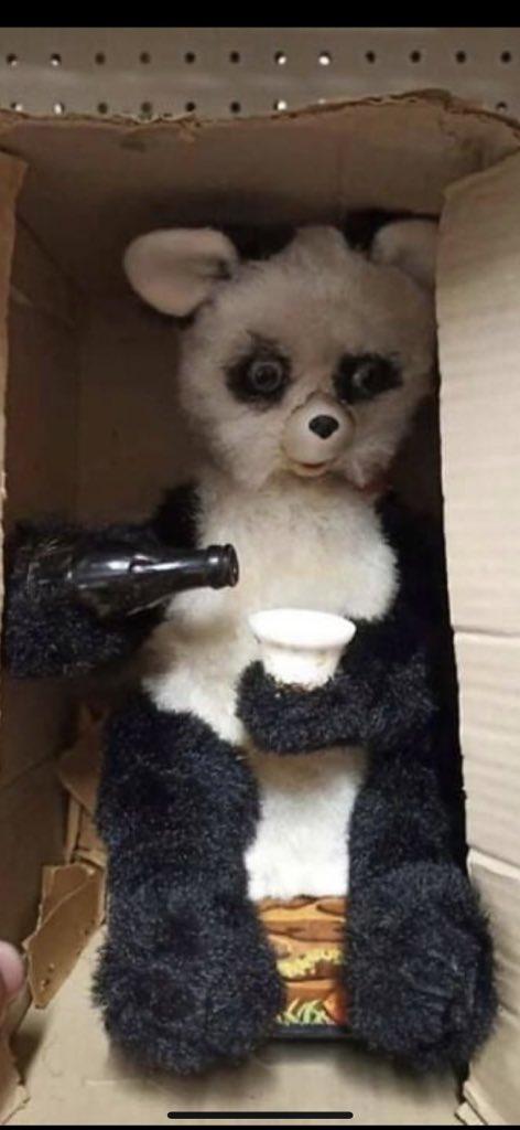 a fucked up teddy bear (?) in a box, with a bottle of beer and a glass of in his hand, having craaaaazy eyes